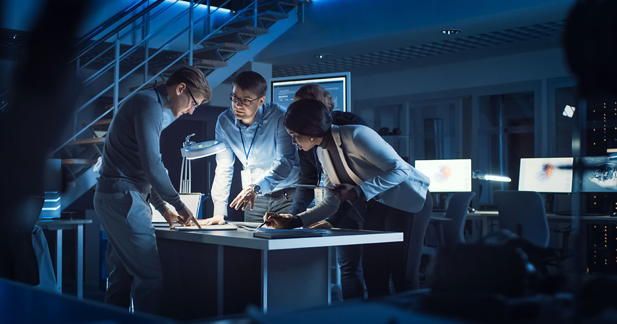 Business team standing around a table doing industry research.