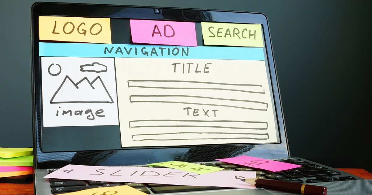 Laptop with post-it notes indicating a website layout design & navigation