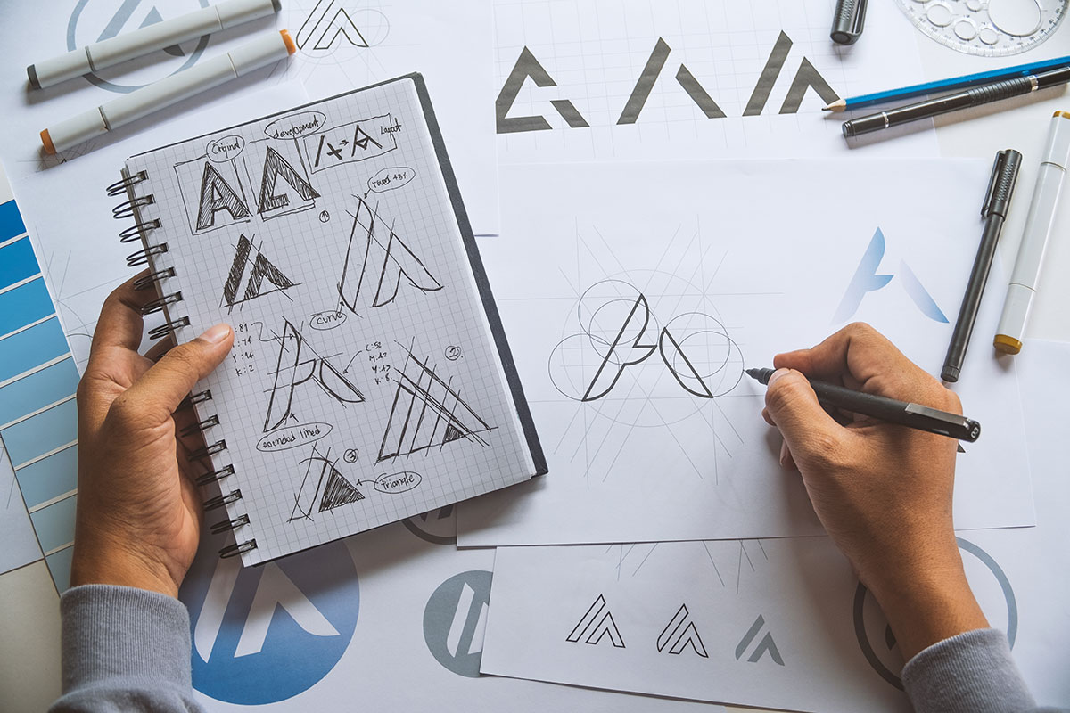 A man hand-drawing samples of logos and branding.