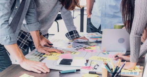 A team is standing at a desk working on brand strategy.