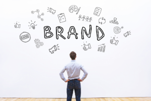 A man is standing in front of a wall that reads "Brand", with icons surrounding the word brand.