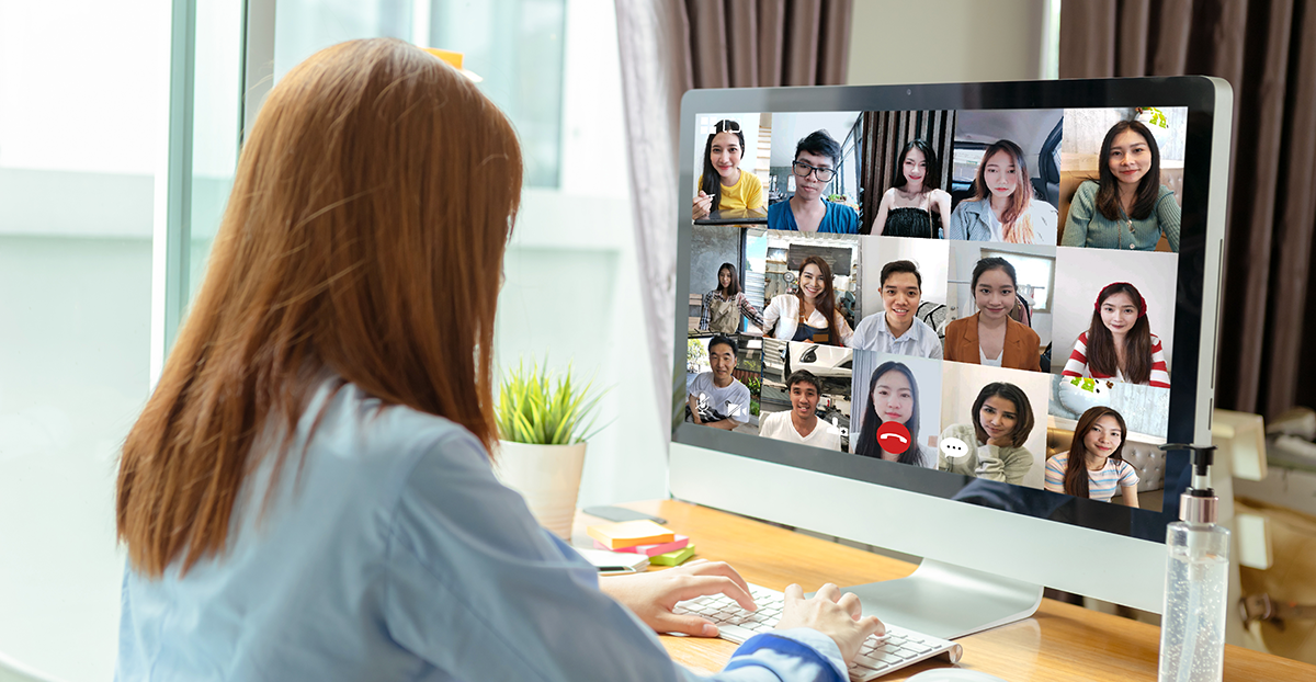 A woman at a computer in an online meeting managing a remote team.