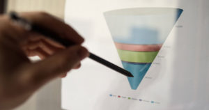 A hand holding a pen pointing at a picture of a Lead Funnel