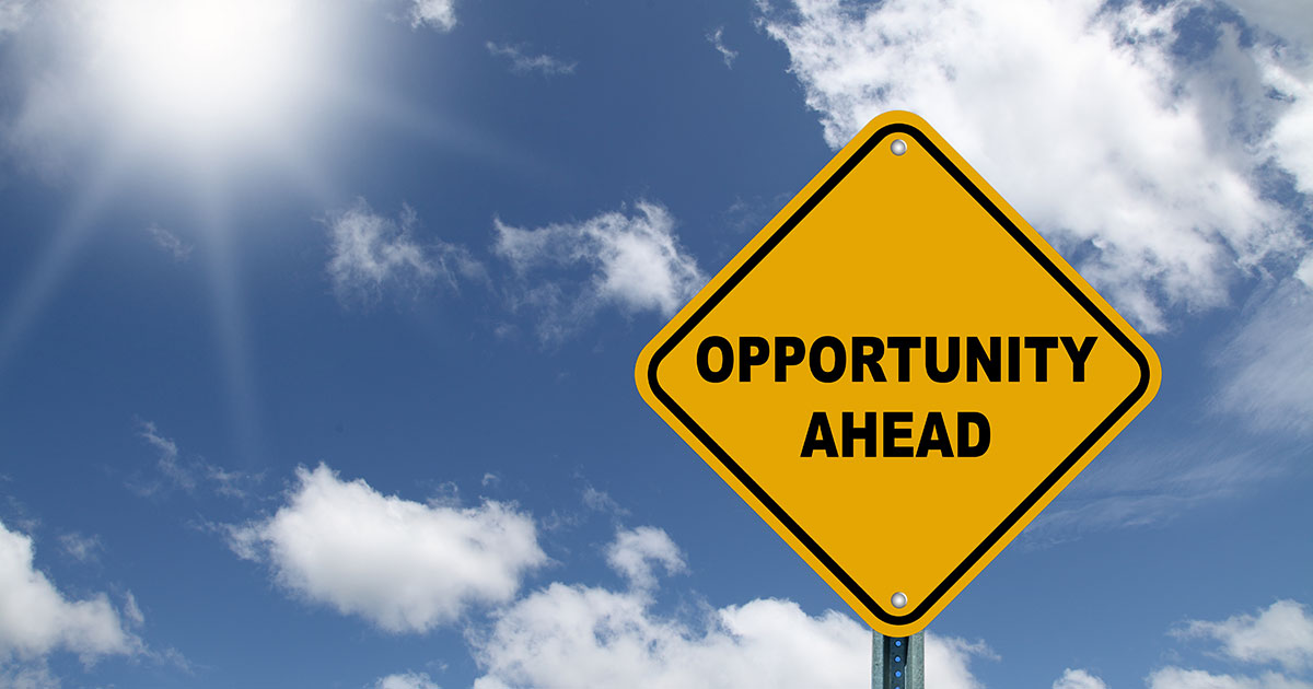 A street sign reading "Opportunity Ahead" with a clear blue sky in the background.