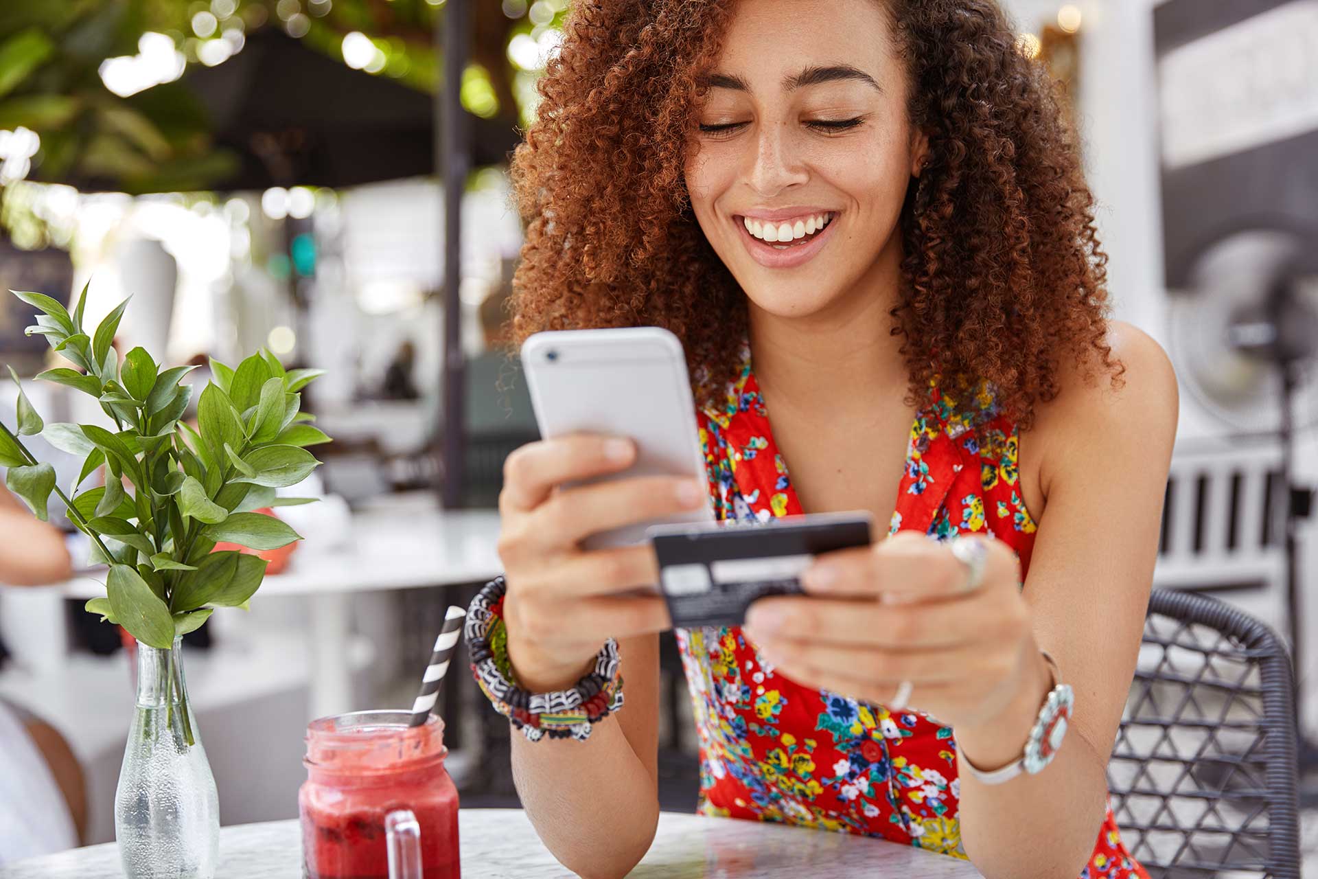 Woman holding her mobile phone in one hand and a credit card in the other, getting ready to make an online purchase.