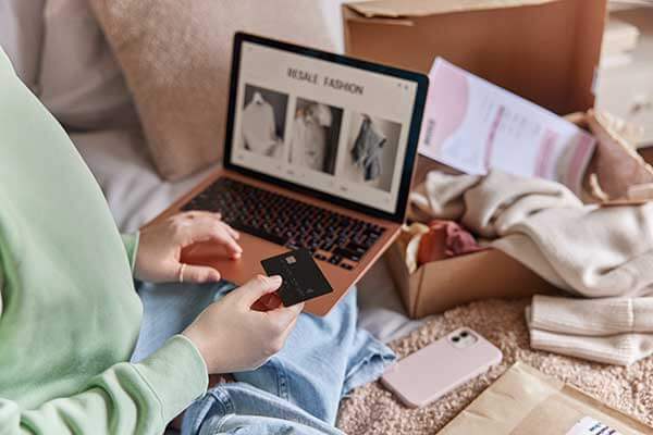 Woman holding credit card in her hand while shopping on a laptop.