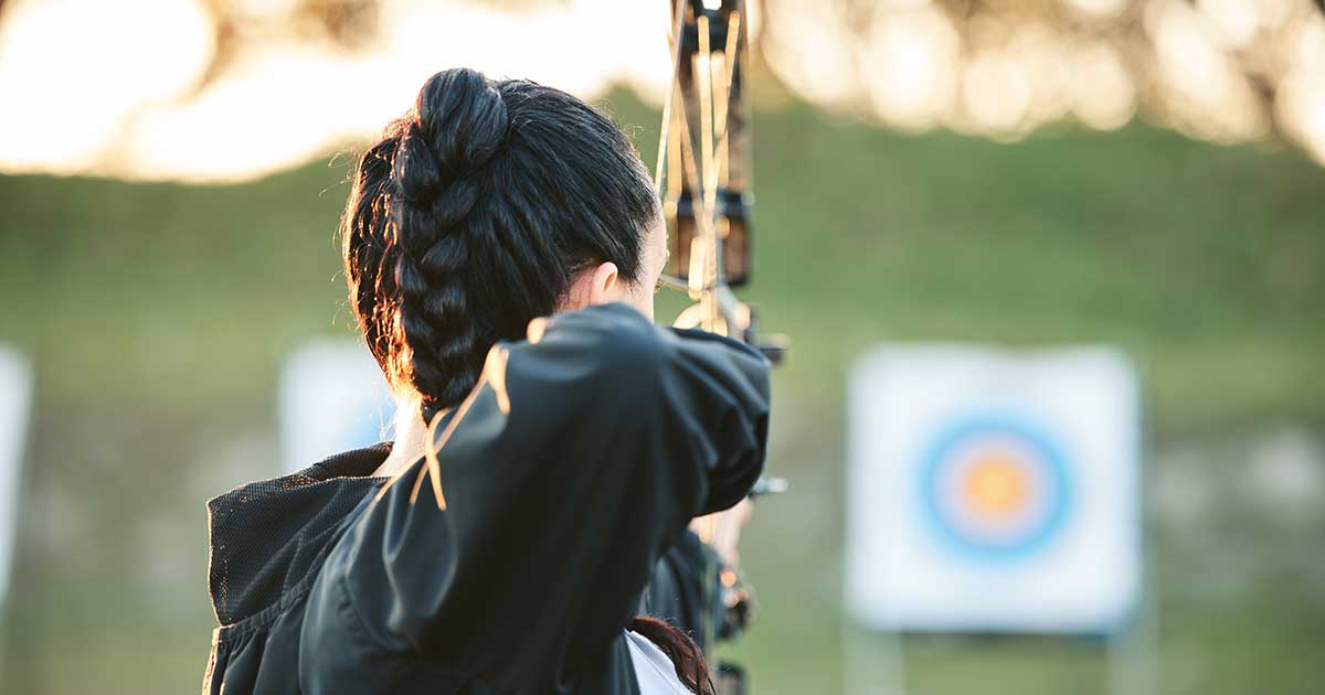 Archer training with bow and arrow shoting at target.
