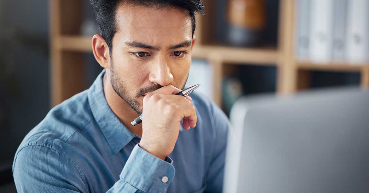 Business man thinking while looking at laptop.