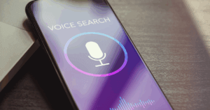 Cell phone sitting on desk with voice search on screen.