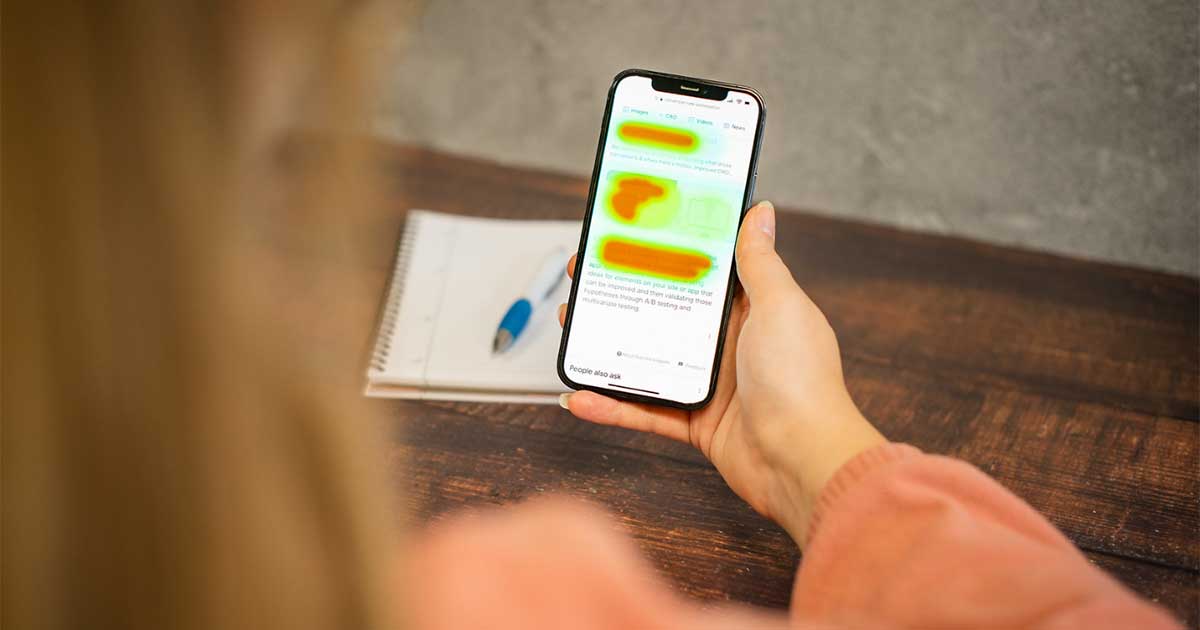 Woman holding mobile phone with a heat mao over screen.