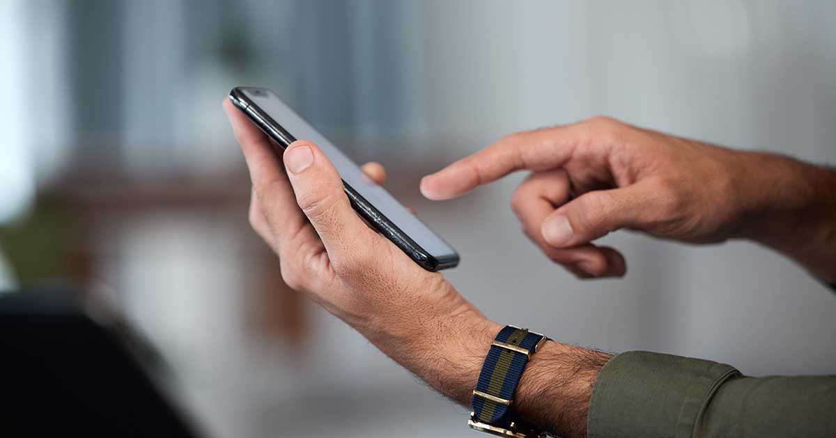 Hands of business man holding mobile phone.