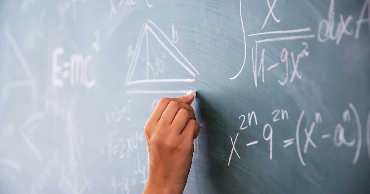 Teacher writing on blackboard.