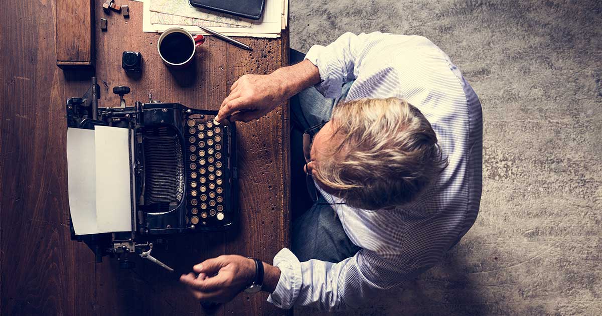 Top view of man typing on typewriter.
