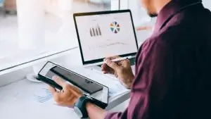 Business leader holding pen pointing at tablet.