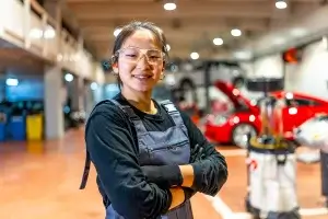 Young female mechanic smiling with crossed arms.